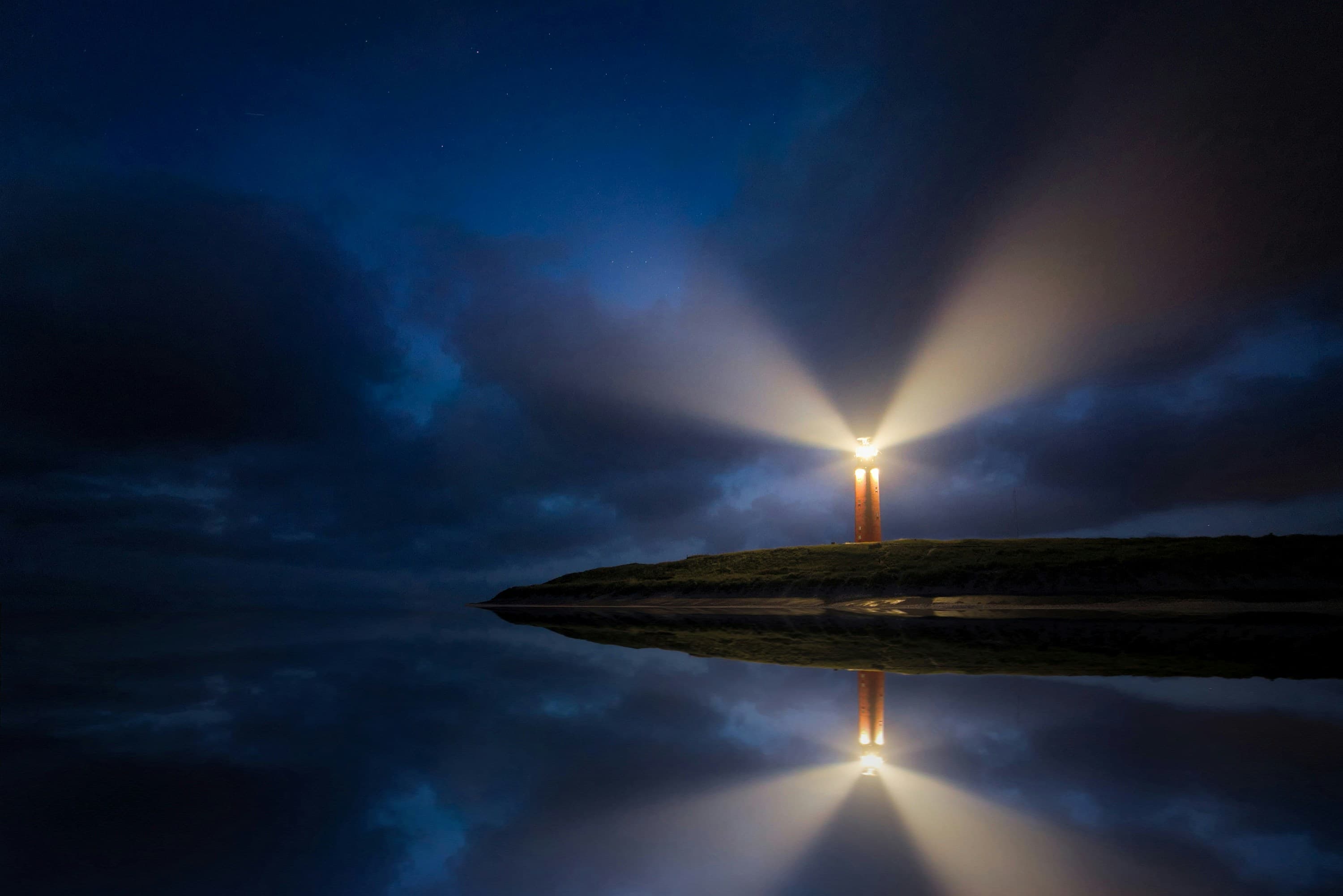 A lighthouse beside still water at night